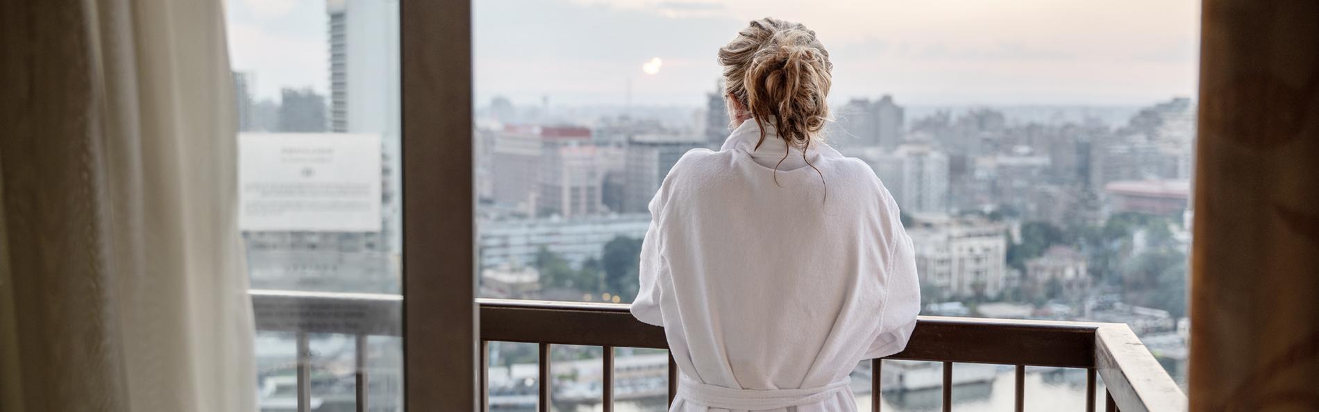 Urlauberin steht im Bademantel auf dem Balkon