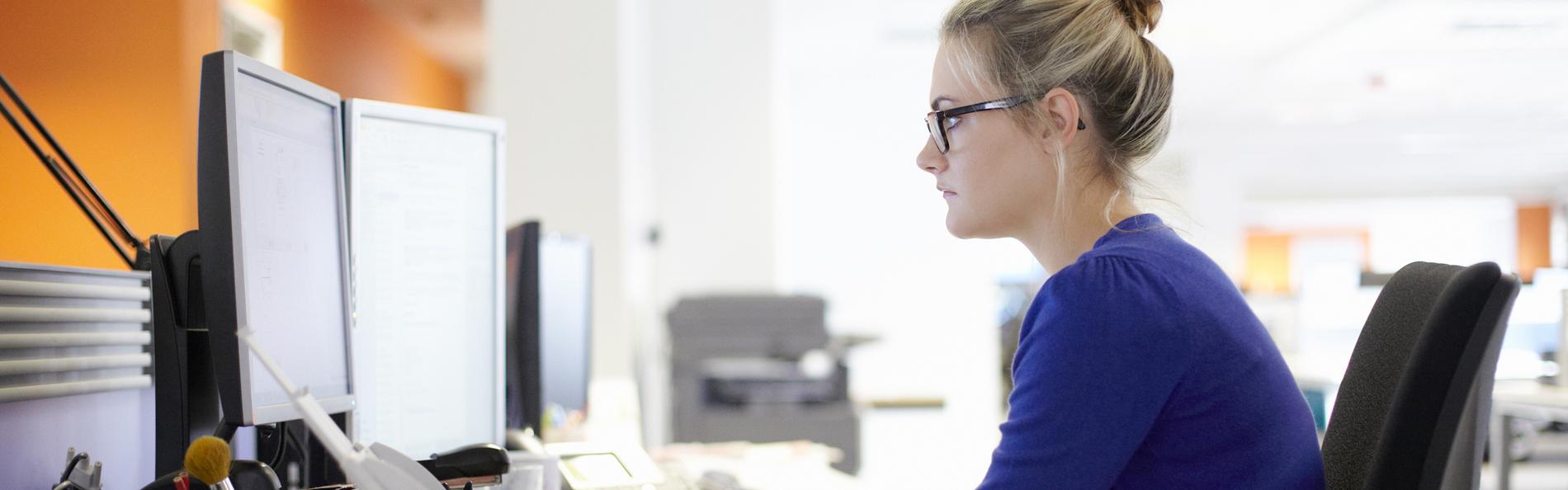 Junge Frau sitzt vor Computer und guckt angestrengt