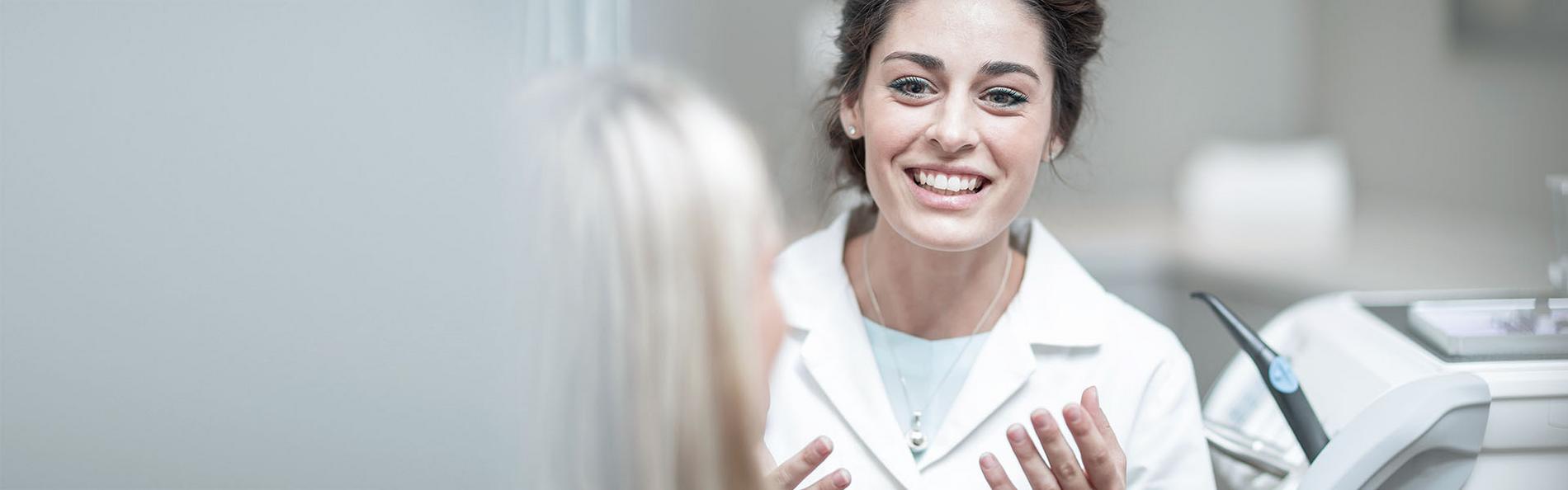 Zahnärztin lächelt ihre Patientin gegenüber an