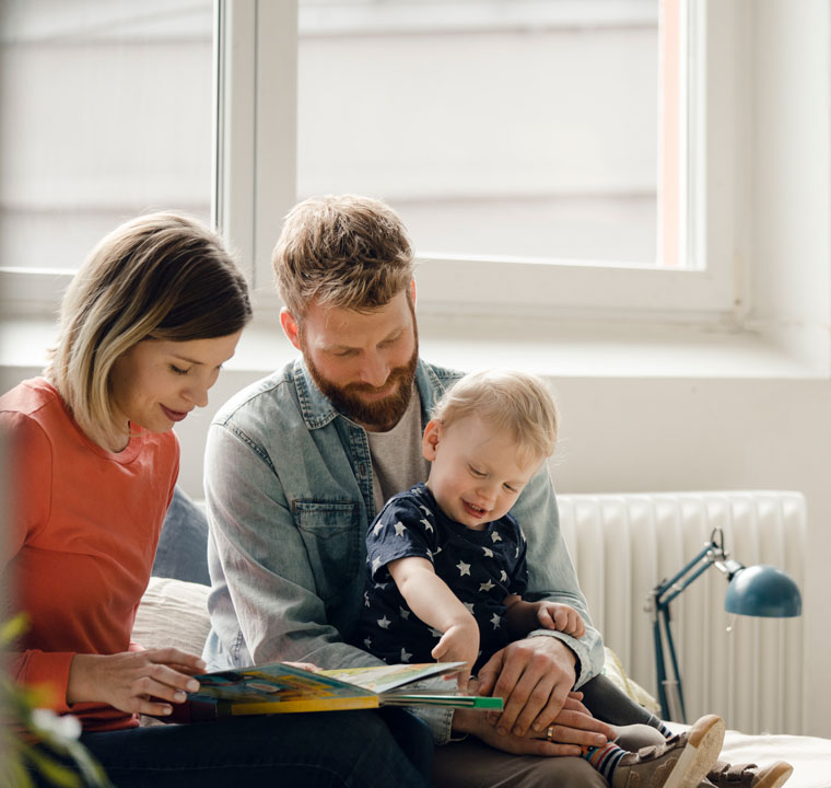 Eltern lesen Kleinkind aus Buch vor