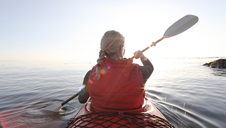 Frau mit Kajak fährt aufs Meer
