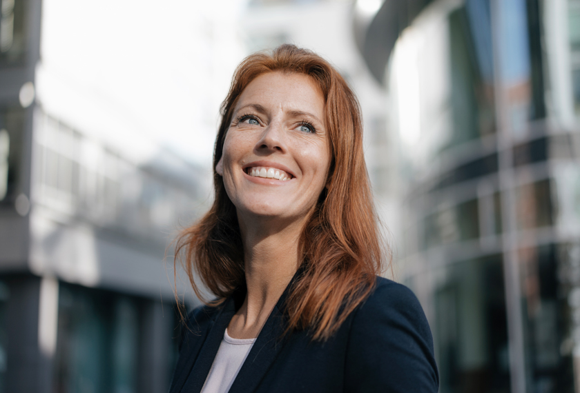 Rothaarige Frau schaut in den Himmel