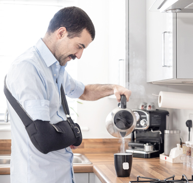 Mann mit Armschlinge giesst Kaffee ein