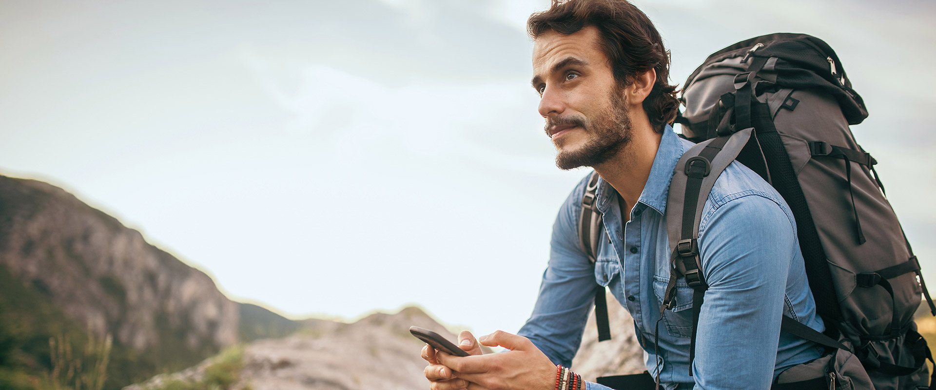 Auslandsservice Junger Mann mit Smartphone und Rucksack