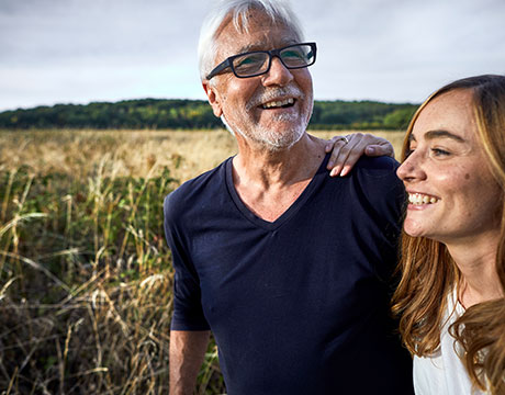 Vater und Tochter spazieren lachend im Feld