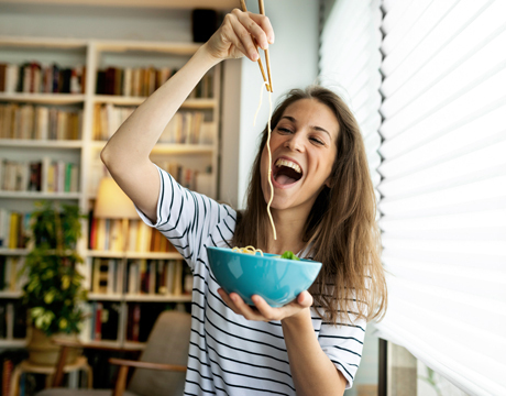 Junge Frau mit Ringelshirt isst Spaghetti aus einer Bowl
